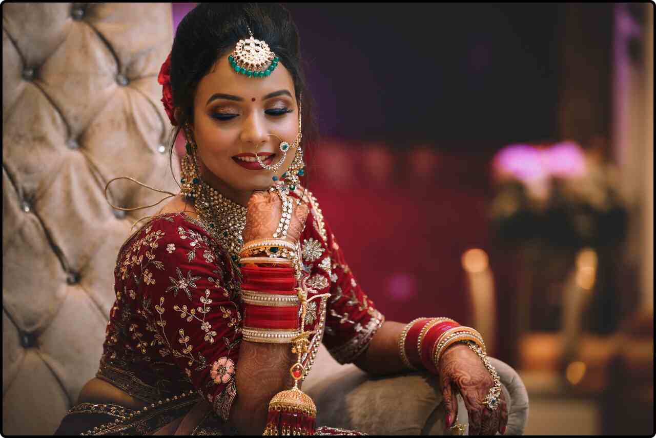 Woman dressed in a red and gold lehenga, adorned with matching jewelry.